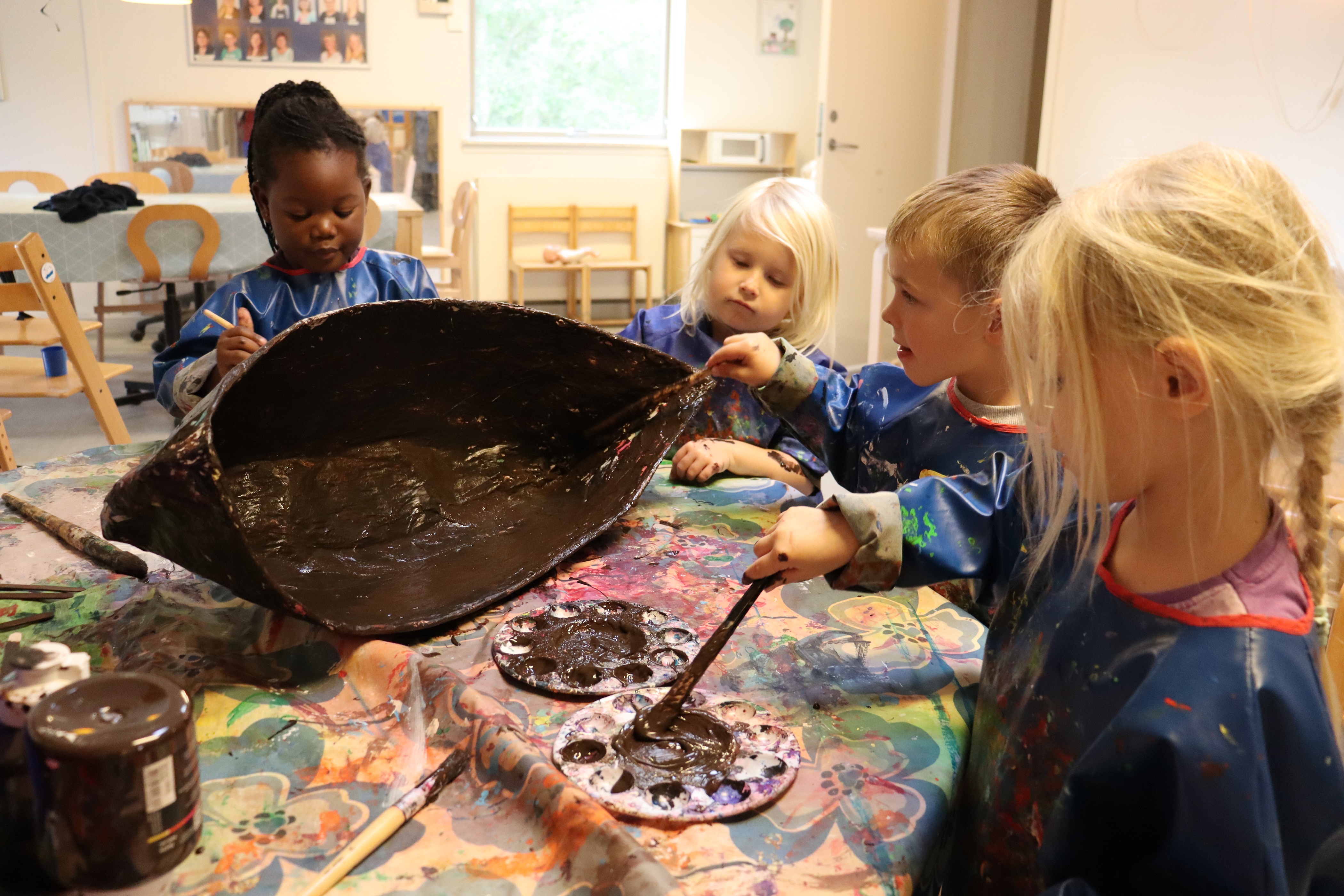 Børn maler på papmache med stor koncentration